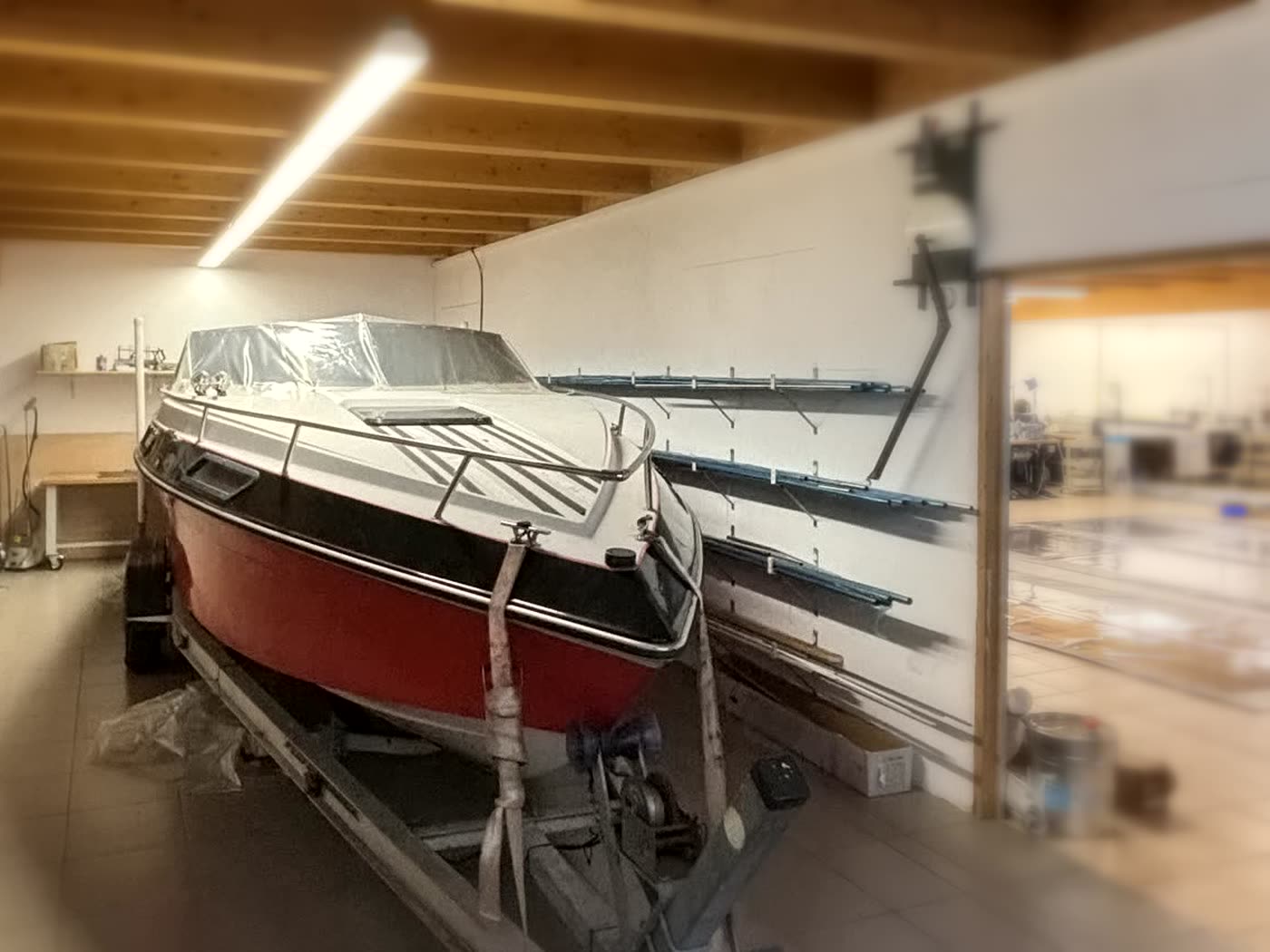 Motorboot auf dem Trailer in der Halle, dahinter die Werkstatt